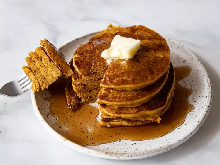 A stake of pumpkin pancakes with butter on top.