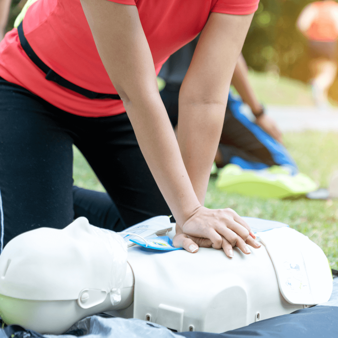 A woman giving CPR training on a dummy.