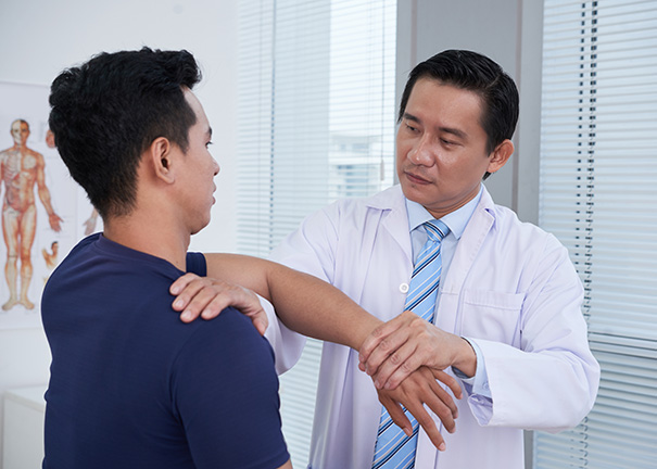 Doctor in white coat provides osteopathic manipulative therapy to a male patient.